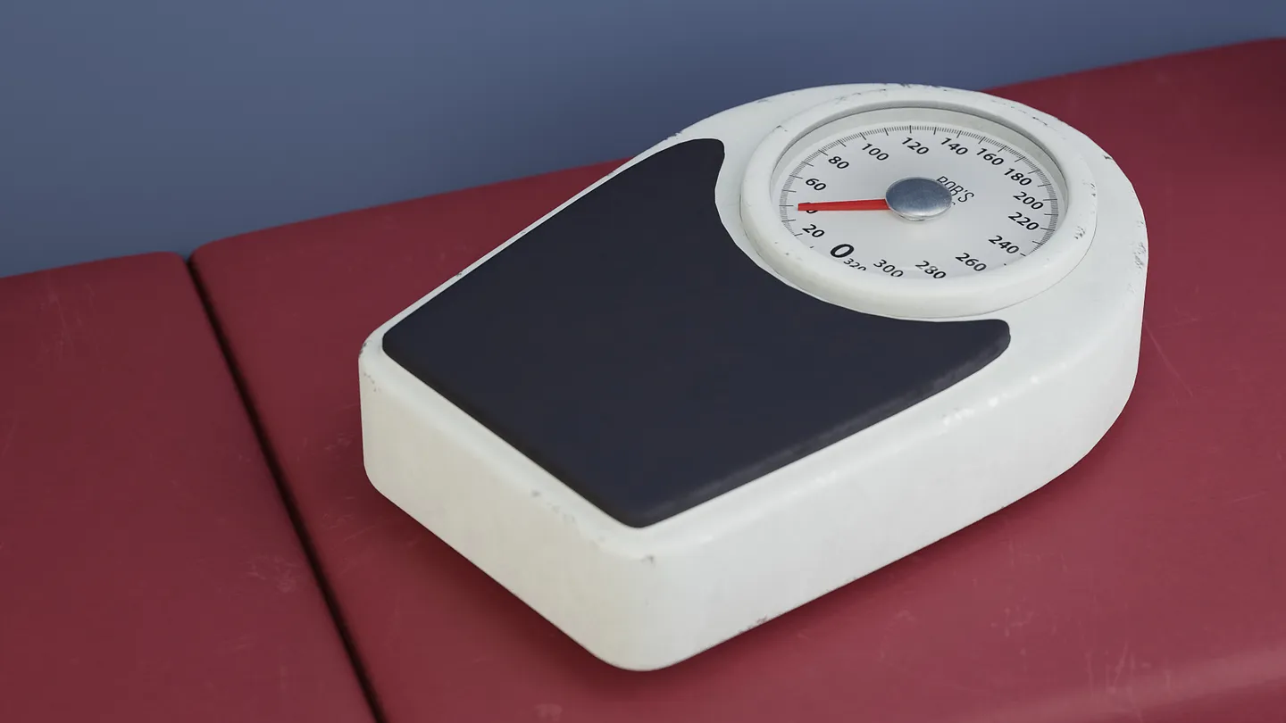 Stylized analog medical scale with a round dial and standing platform.